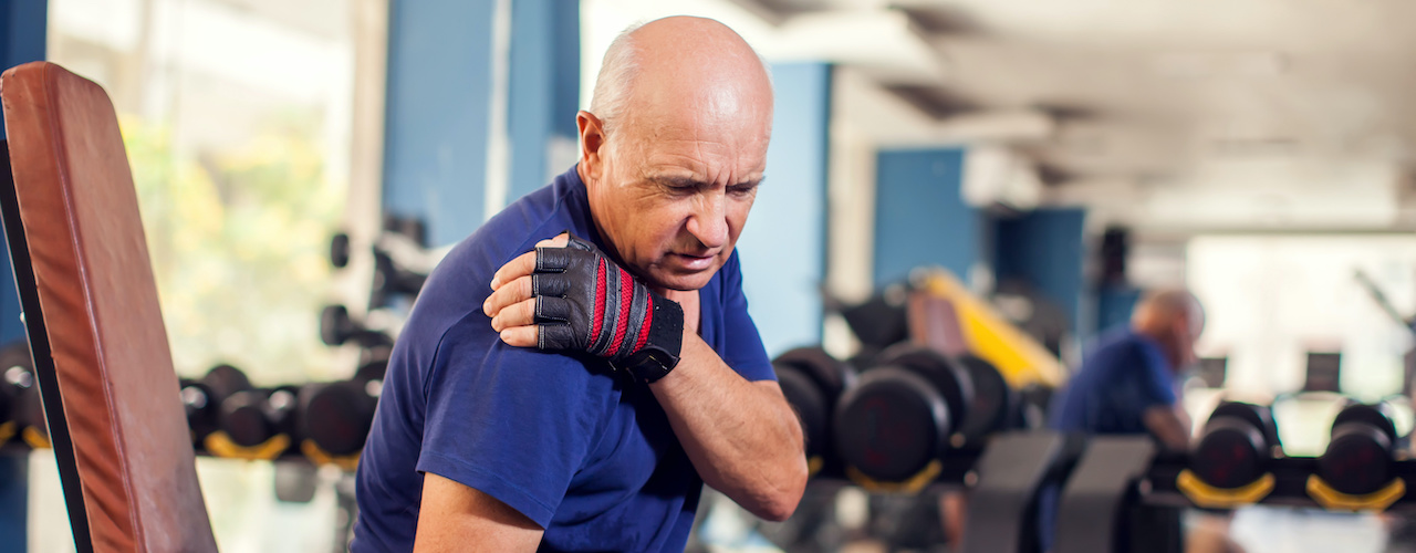 Older man experiencing shoulder pain at the gym
