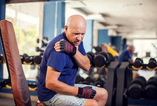 Older man experiencing shoulder pain at the gym