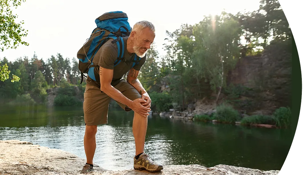older man with painful knee while hiking